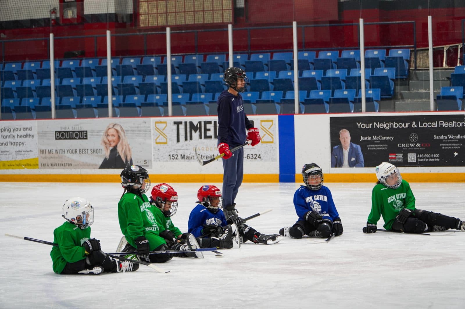 Young campers in a small group on the ice with their coach